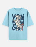A light blue short-sleeve t-shirt featuring a graphic print of a dachshund wearing a white tank top and red shorts, with the text 'YOM WONA GO' in dark blue brush lettering.