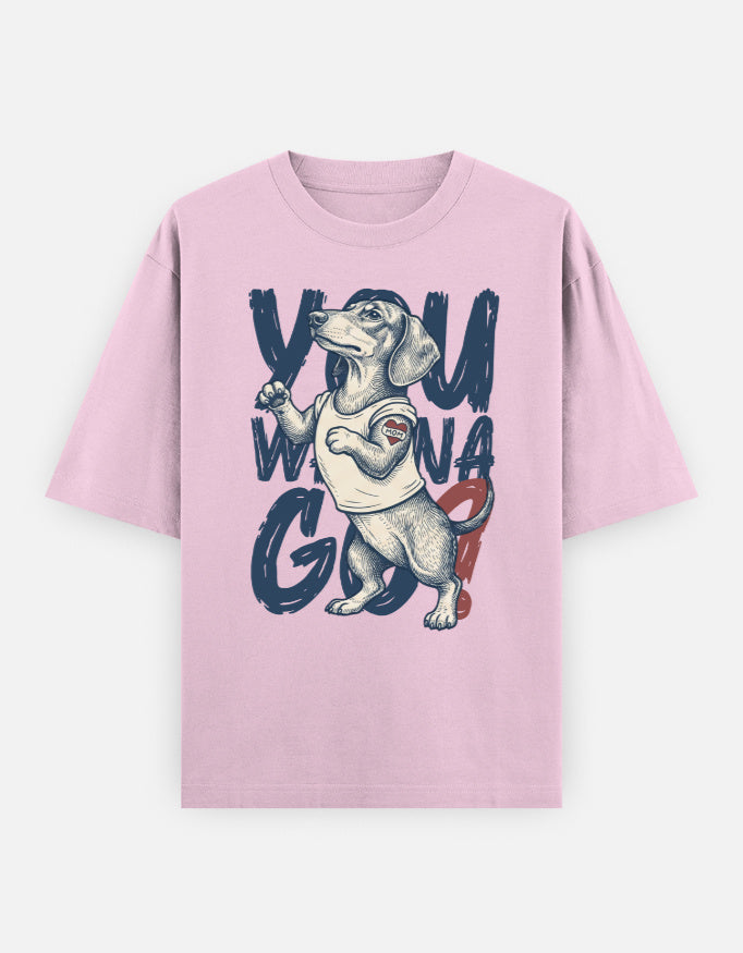 A light pink short-sleeve t-shirt with a graphic print of a dachshund wearing a white tank top, surrounded by the text 'YOU WONA GO'.